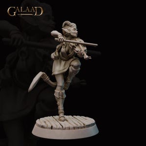 May include: A gray painted miniature figurine of a female elf playing a violin. The elf is wearing a long, flowing robe and has a mischievous expression on her face. The figurine is standing on a wooden base.