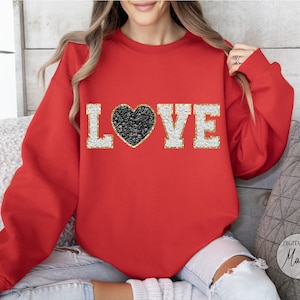 May include: Red sweatshirt with a gold glitter "LOVE" design featuring a black glitter heart.