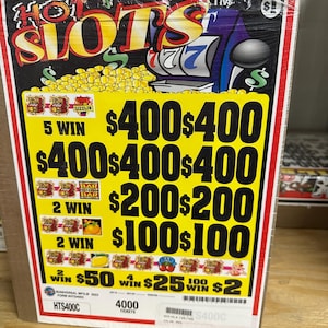 May include: A package of "Hot Slots" scratch-off lottery tickets. The tickets have a yellow background with various prize amounts, including $400, $200, $100, $50, $25, and $2. The top of the ticket features a slot machine graphic.