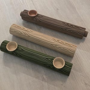 May include: Three wooden pipes with a tree bark design. The pipes are in brown, beige, and green. Each pipe has a small bowl at one end.