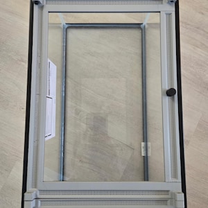 May include: A rectangular terrarium with a grey frame and a glass front. The top section displays a digital screen showing temperature and humidity readings. The bottom of the terrarium has the text "INNO XED".