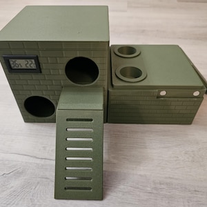 Könnte beinhalten: Ein grünes mehrstöckiges Spielhaus für Kleintiere mit einer Rampe, zwei Öffnungen und einem digitalen Display, das 36 % und 22 anzeigt. Das Spielhaus ist aus einem strukturierten Material gefertigt, das an Ziegel erinnert.