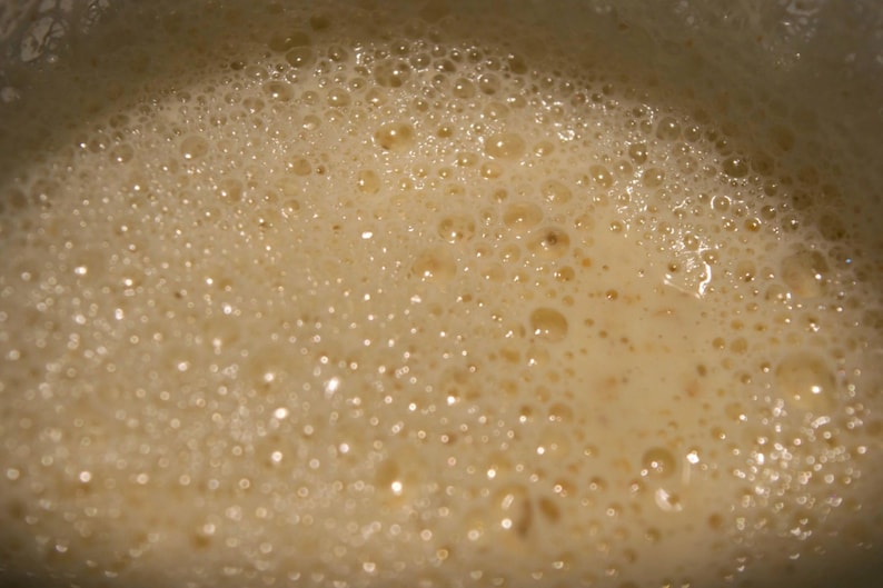 May include: Close-up of a light brown liquid with small bubbles on the surface.
