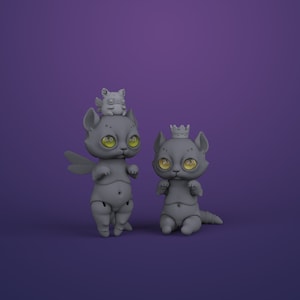 2 gray digital articulated cat dolls in a royal purple studio. Right one with yellow eyes sits and has a crown, left one with green eyes stands and has dragonfly wings and cute chubby winged animal on its head.