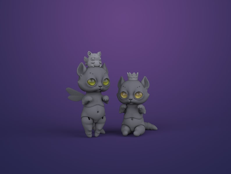 2 gray digital articulated cat dolls in a royal purple studio. Right one with yellow eyes sits and has a crown, left one with green eyes stands and has dragonfly wings and cute chubby winged animal on its head.