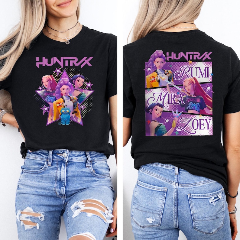 May include: Black t-shirt featuring the text "HUNTRAX" in purple, with a graphic of several animated characters. The back of the shirt displays the names Rumi, Mira, and Zoey, also with character graphics. A stylish tee.