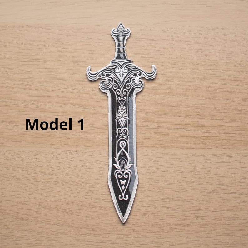 May include: A decorative sword with intricate silver-colored detailing on a black blade. The hilt and blade feature ornate patterns. The text "Model 1" is printed in black on the wooden surface.