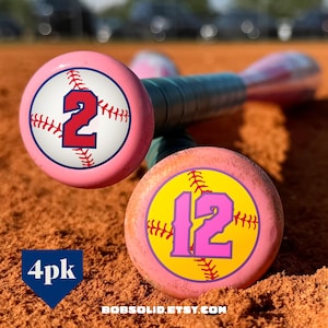 May include: Pink baseball bats with baseball stitching and the numbers 2 and 12 in red and pink. The bats are on a brown surface. The text "4pk" is in a blue diamond shape. The website address "BOBSOLID.ETSY.COM" is at the bottom.