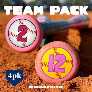 May include: Pink baseball bats with the text "TEAM PACK". One bat has the number 2 in red, and the other has the number 12 in pink. The bats are on a brown surface. The text "4pk" and "BOBSOLID.ETSY.COM" are also visible.