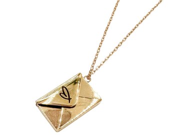 Könnte beinhalten: Eine goldene Kettenkette mit einem goldenen Anhänger in Form eines Umschlags. Der Umschlag hat ein Herz auf der Vorderseite.