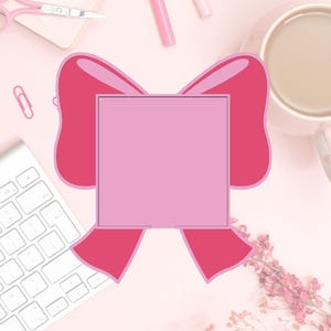 May include: A pink-themed flat lay featuring a large pink bow shape with a square center. A white keyboard, pink scissors, a cup of coffee, and other stationery items are arranged on a light pink surface.