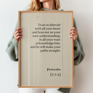 Op de afbeelding: Een ingelijste print met een lichtbeige achtergrond en een houten frame. De print bevat de tekst "Vertrouw op Jehovah met heel je hart..." en het woord "Spreuken" met de versverwijzing [3:5-6].