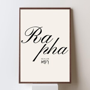 Peut inclure: Une affiche encadrée avec le mot "Rapha" en écriture noire élégante. En dessous, le mot "HEALER" et du texte hébreu sont affichés. L'œuvre est sur un fond crème, encadrée dans un cadre marron foncé.