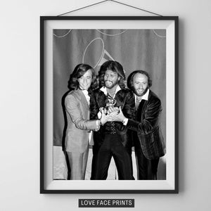 Puede incluir: Impresión en blanco y negro enmarcada que muestra a tres hombres con trajes y chaquetas sosteniendo un premio. La impresión está etiquetada "LOVE FACE PRINTS" en la parte inferior. Imagen de retrato.