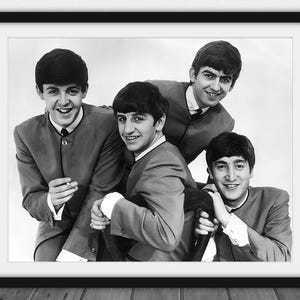 May include: Black and white framed photograph of The Beatles. The four men are wearing matching suits and smiling. The image is a classic portrait of the iconic band.