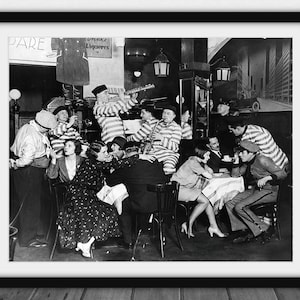 May include: Black and white framed print depicting a restaurant scene. A band in striped uniforms plays music while people sit at tables. The sign reads "PARE" and "Drinks Liqueurs".