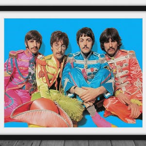 May include: Framed print featuring a vibrant image of four men in colorful military-style jackets and pants against a bright blue background. The men are posed closely together, with a large hat in the foreground. The jackets are in shades of pink, yellow, and blue.