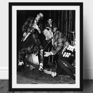 Könnte beinhalten: Schwarz-weiß gerahmtes Foto einer Band, die auf einer Bühne auftritt. Die Musiker tragen karierte Jacken und spielen Instrumente wie Saxophon, Gitarre und Kontrabass. Das Bild ist eine mittlere Aufnahme.