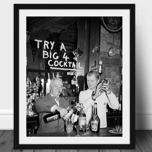 Puede incluir: Impresión enmarcada en blanco y negro de una escena de bar vintage. Dos camareros preparan cócteles detrás de una barra. El letrero sobre la barra dice "TRY A BIG 4 COCKTAIL". Se ven botellas y vasos en la barra.
