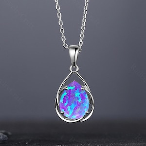 Op de afbeelding: Een zilveren ketting met een traanvormige hanger met een levendige blauwe en paarse opaal edelsteen.