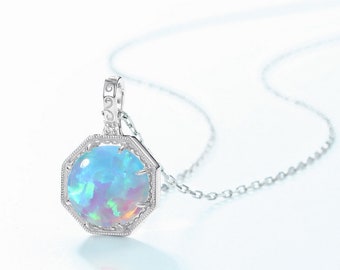Puede incluir: Un collar de plata con una cadena delicada y un colgante con una piedra de ópalo azul engastada en un marco octogonal de plata.