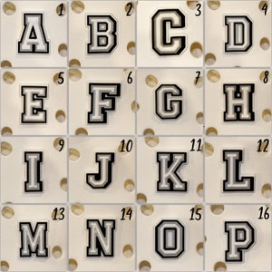 May include: A set of 16 white and black felt letters, A through P, with a white background. Each letter is outlined in black and has a white border.