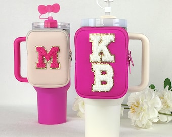 Puede incluir: Dos vasos térmicos rosas y blancos con una funda de neopreno rosa. Las fundas tienen una cremallera y un asa. Una funda tiene la letra "M" en purpurina dorada y la otra tiene las letras "KB" en purpurina dorada.