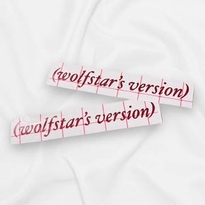 May include: Two white rectangular stickers with the text "(wolfstar's version)" in a red, cursive font. The stickers have a red grid pattern and are placed on a white, textured background.