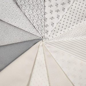 May include: A collection of ten fabric samples in various shades of white and gray with different patterns, including small floral prints, stripes, and dots.