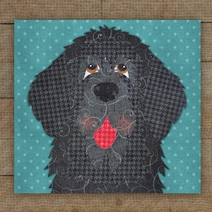 May include: A square fabric art piece featuring a black dog with a houndstooth pattern. The dog has brown eyes and a red tongue. The background is a teal fabric with white polka dots. The dog's fur has a decorative swirl design.