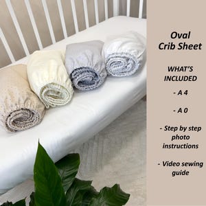 May include: Four rolled oval crib sheets in beige, cream, gray, and white, with a white crib in the background. The text "Oval Crib Sheet" and "WHAT'S INCLUDED" are visible.