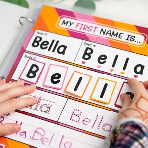 Puede incluir: Una colorida hoja de actividades educativas en una carpeta, con el nombre "Bella". La hoja incluye secciones para leer, deletrear y construir el nombre con fichas de letras. El título dice "MY FIRST NAME IS..."