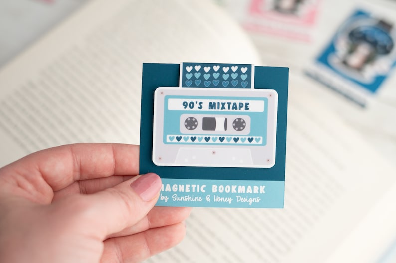 May include: A teal magnetic bookmark featuring a retro cassette tape design with the text "90's Mixtape." The bookmark has a white background with light blue accents and heart details. The text "MAGNETIC BOOKMARK" is also visible.
