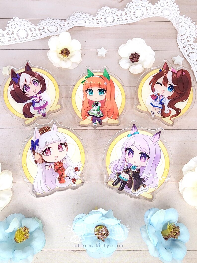 May include: Five clear acrylic charms featuring chibi-style anime characters with animal ears, each set against a circular yellow background. The characters have distinct hair colors including brown, orange, and light purple, wearing detailed outfits.