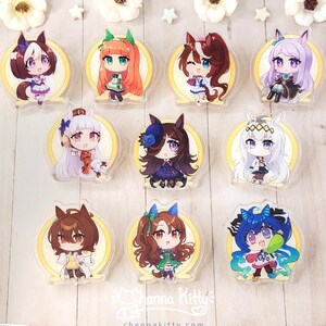 May include: A collection of nine acrylic charms featuring chibi-style anime characters with animal ears, each set against a circular yellow background. The charms display various hair colors and outfits. Text at the bottom reads Chenna Kitty.