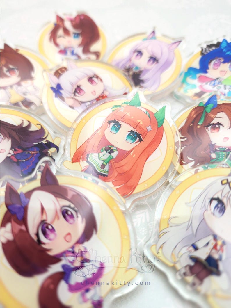 May include: A collection of circular acrylic charms featuring various anime-style characters with colorful hair and outfits. Each charm is set against a yellow circular background. The text "Chenna Kitty" and "chennakitty.com" is visible.