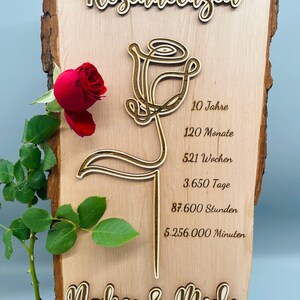 May include: A wooden sign with a carved rose design and the text "Rosenhochzeit" (German for "Rose Wedding"). The sign also includes the text "10 Jahre", "120 Monate", "521 Wochen", "3.650 Tage", "87.600 Stunden", "5.256.000 Minuten", "Nadine & Michi", and "09. April 2025".