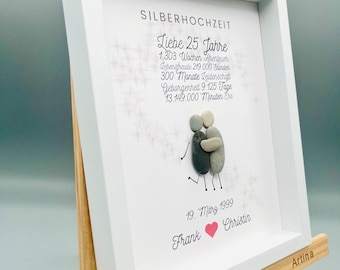 May include: A white framed picture with a silver background and a gray pebble couple holding hands. The text reads "Silver Anniversary, Love 25 Years, 1,303 Weeks of Adventure, 219,000 Hours of Joy, 300 Months of Passion, 9,125 Days of Togetherness, 13,149,000 Minutes of Love, March 19, 1999, Frank, Christin".