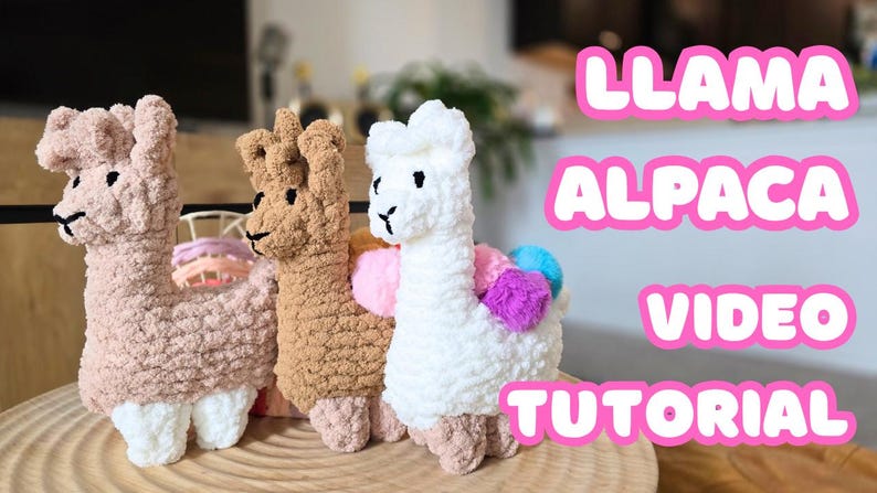 May include: Three crocheted llama and alpaca plush toys in pink, brown, and white. The toys are sitting on a wooden surface. The text "LLAMA ALPACA VIDEO TUTORIAL" is in pink letters on a white background.