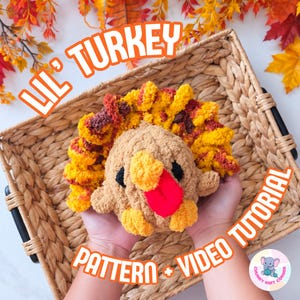 May include: A plush turkey toy made of tan, yellow, orange, and red yarn with black eyes and a red wattle. The text LIL' TURKEY PATTERN + VIDEO TUTORIAL is displayed in orange. The turkey is held over a woven basket with autumn leaves in the background.