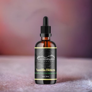May include: A brown glass bottle with a black dropper top and a black label. The label says "Old Fashioned Lounge" and "Vanilla Bitters" with the text "Real Vanilla Beans from Madagascar Island" in smaller font. The bottle contains 2 fl oz / 59 ml.