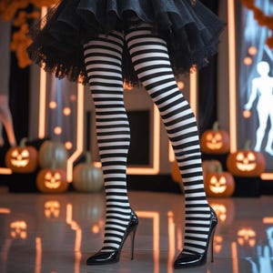 May include: Black and white horizontally striped tights paired with black high-heeled pumps. The tights feature a consistent pattern of narrow stripes extending from the upper thigh down to the feet, worn under a black tulle skirt.
