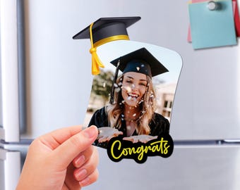 May include: A black and white photo of a graduate wearing a black cap and gown, with confetti falling around her. The photo is on a black background with a yellow "Congrats" text.