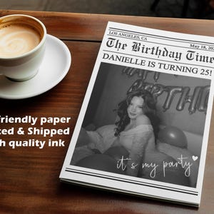 Può includere: Una stampa in bianco e nero in stile giornale con il titolo "The Birthday Time" e il testo "Danielle compie 25 anni!". È presente una foto di una donna. Una tazza di caffè è su un piattino.