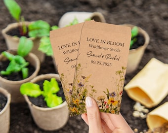 May include: Two brown paper packets with wildflower seeds. The packets have a floral design and the text "LOVE IN BLOOM Wildflower Seeds Samuel & Rachel 09.25.2025".