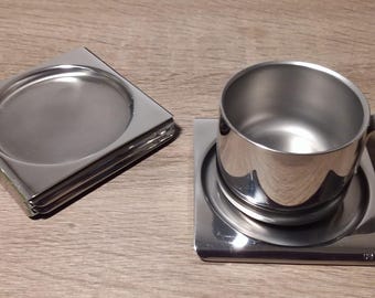 Pode incluir: Dois  copos de aço inoxidável, um com forma redonda e o outro quadrado, com uma xícara de aço inoxidável no copo quadrado.