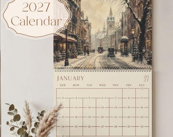 Puede incluir: Un calendario de pared para 2027 con una ilustración de una escena callejera invernal de estilo vintage en la parte superior. La página del calendario muestra el mes de enero con una cuadrícula para las fechas, etiquetada con los días de la semana.