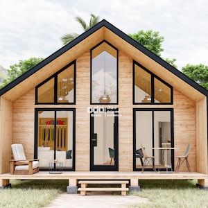 K&ouml;nnte beinhalten: Eine moderne Holzh&uuml;tte mit einem gro&szlig;en, dreieckigen Fenster und einer schwarzen T&uuml;r. Die H&uuml;tte hat eine Holzterrasse und ist von &uuml;ppigem Gr&uuml;n umgeben.