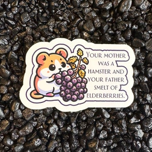 May include: A sticker with a cartoon hamster eating a bunch of purple elderberries. The sticker has the text "Your mother was a hamster and your father smelt of elderberries."