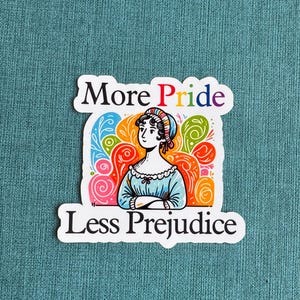 May include: A sticker with a colorful floral design and a woman's illustration. The text on the sticker reads "More Pride Less Prejudice".